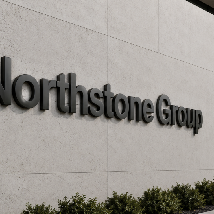 Schwarze 3D-Buchstaben "Northstone Group" an heller Betonfassade neben großen Glasfenstern, niedrige Büsche am Gebäudefuß.