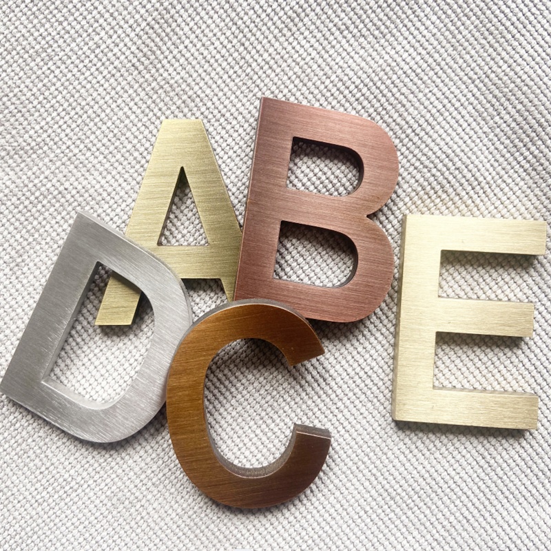 Metallische Buchstaben A bis E auf hellem Stoffhintergrund angeordnet