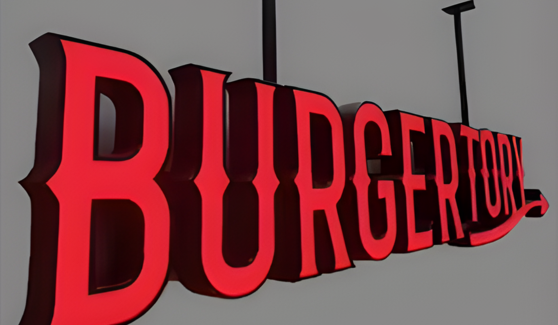 Leuchtendes rotes Burger Town-Schild in großer 3D-Schrift an grauer Wand