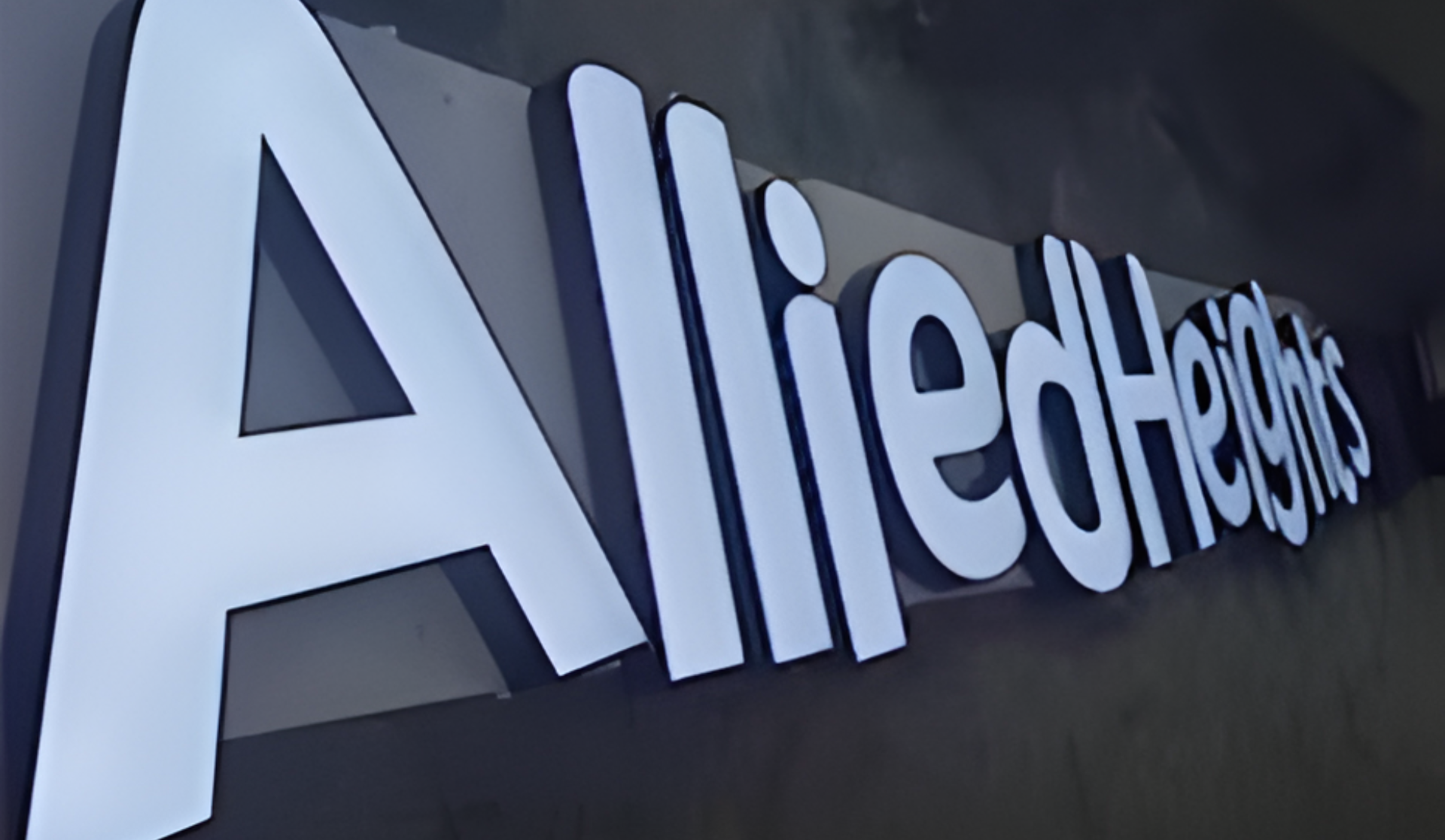 3D-Leuchtschrift „Allied Healths“ an einer dunklen Wand