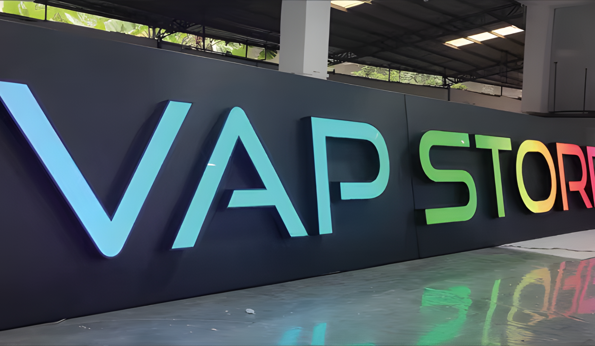 Großes farbiges „VAPSTOR“-Schild an einer dunklen Wand in einer überdachten Halle