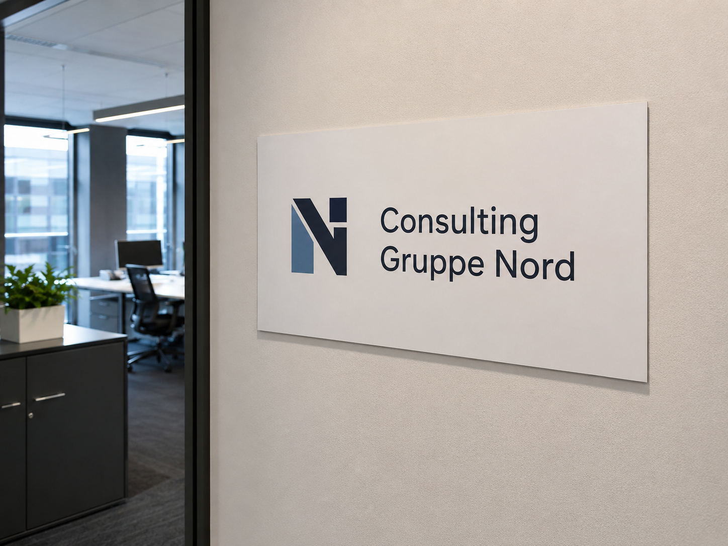 Schild an Bürowand mit blauem N‑Logo und Schriftzug "Consulting Gruppe Nord", im Hintergrund offenes Büro mit Schreibtischen und Pflanze.
