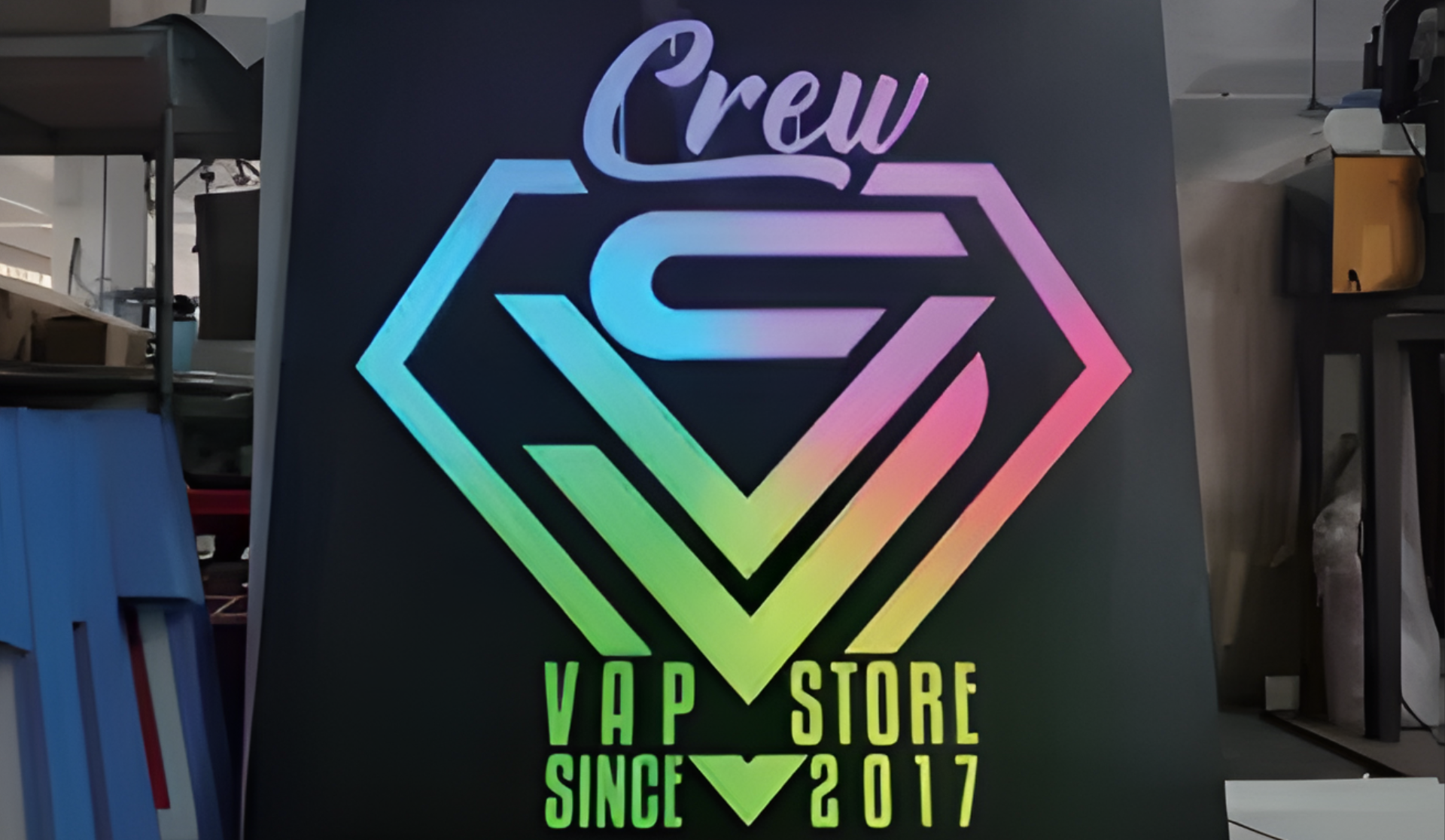 Neonfarbenes Schild mit Superhelden-Logo und der Aufschrift Crew Vap Store Since 2017 in einem Ladeninterieur