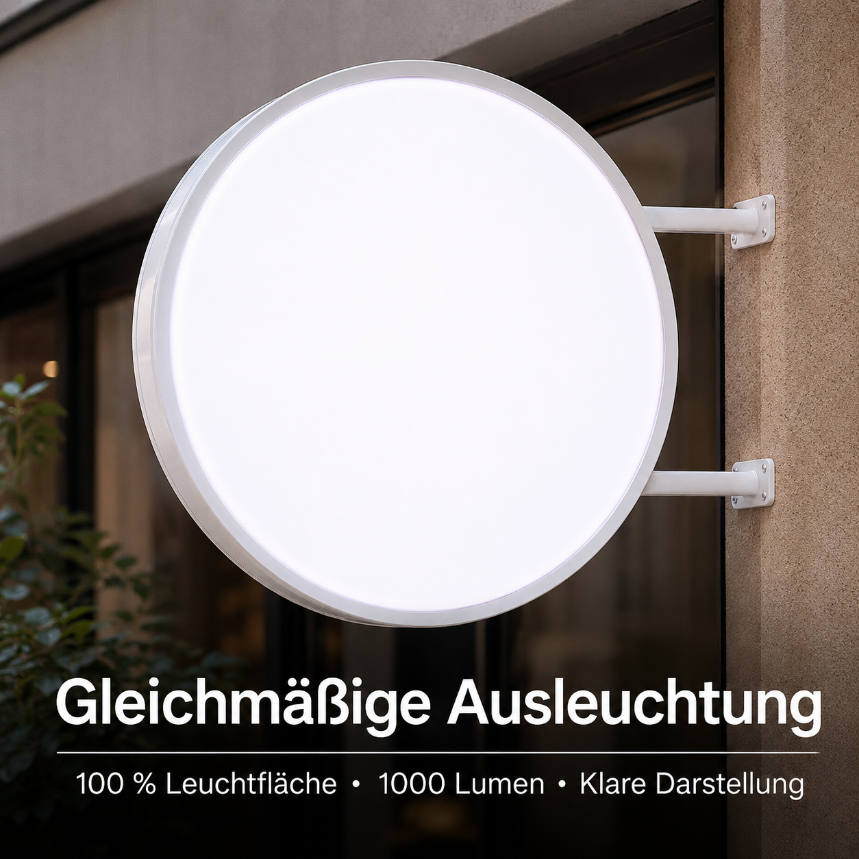 Rundes, leuchtendes Weißschild seitlich an einer Gebäudewand montiert, darunter Text: „Gleichmäßige Ausleuchtung, 100 % Leuchtfläche • 1000 Lumen • Klare Darstellung“.