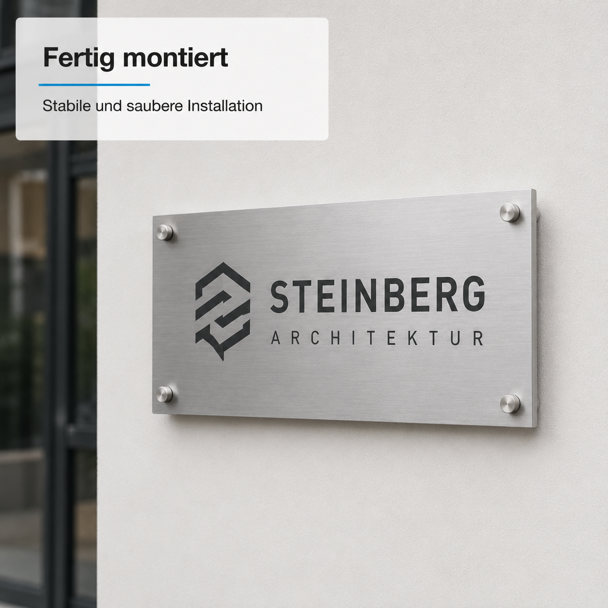 Edelstahl-Türschild mit Logo und Schriftzug "STEINBERG ARCHITEKTUR" seitlich an heller Außenwand montiert, vier Schrauben sichtbar.