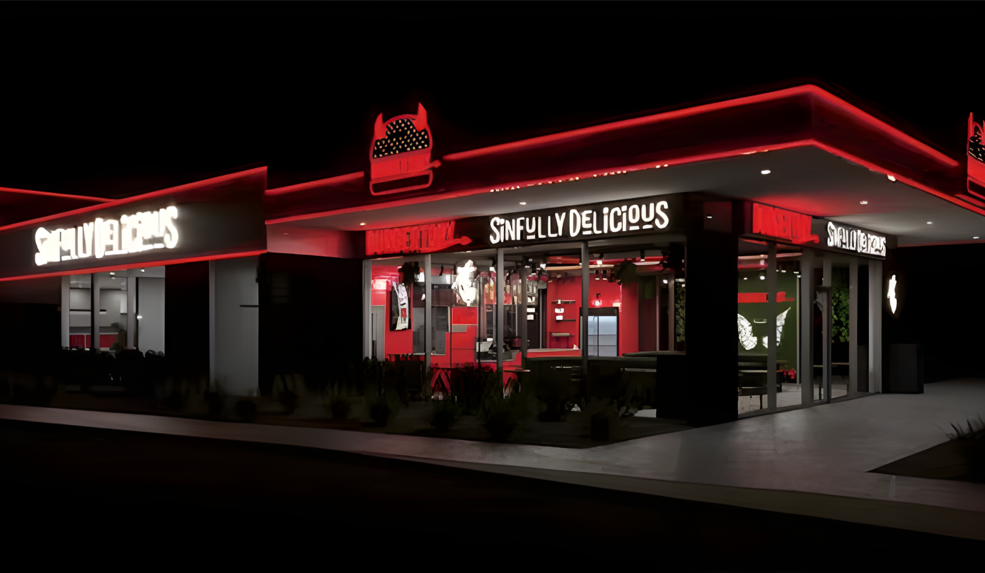 Modernes Fast-Food-Restaurant bei Nacht mit rot beleuchteter Fassade und dem Schild „SINFULLY DELICIOUS“