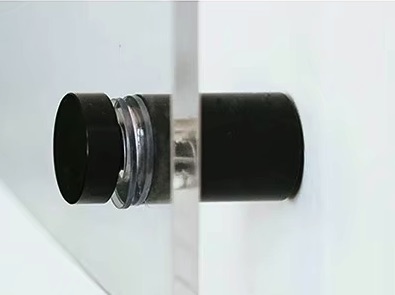Schwarzes Rundrohr mit etwas Glasdichtung, durch eine transparente Glasplatte gesteckt, seitliche Nahaufnahme auf weißem Hintergrund.