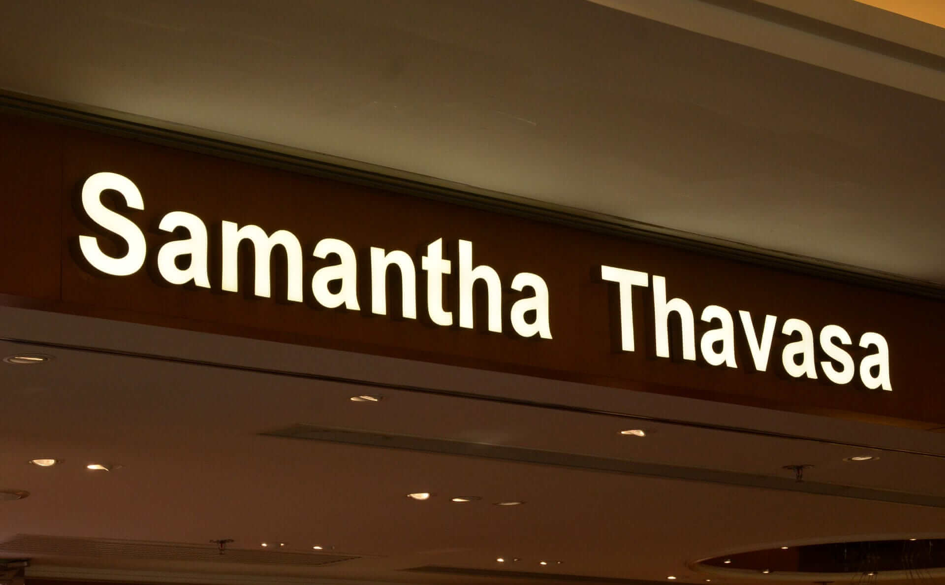 Leuchtende Schilderbuchstaben „Samantha Thavasa“ an der Fassade eines Geschäfts in einem Einkaufszentrum.